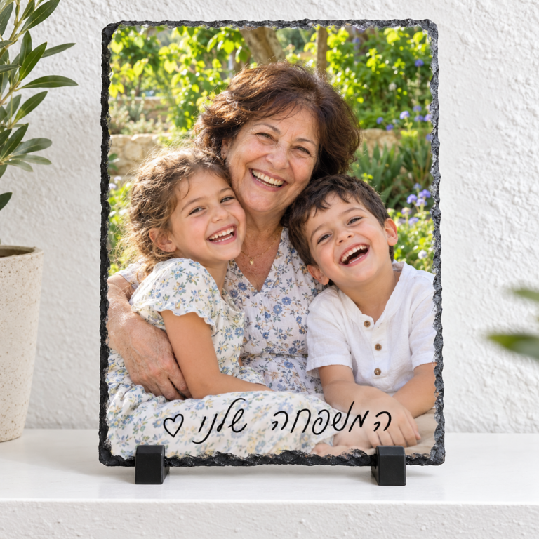 אבן בזלת לאורך 15×21 עם תמונת סבתא ונכדים וכיתוב המשפחה שלנו על מעמדים שחורים מול קיר בטון לבן מחוספס