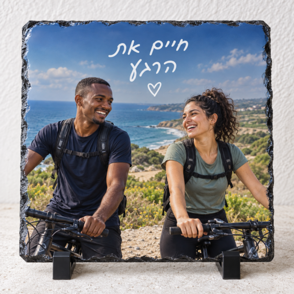 אבן בזלת ריבועית עם חברים ברכיבת אופניים וכיתוב לבן חיים את הרגע