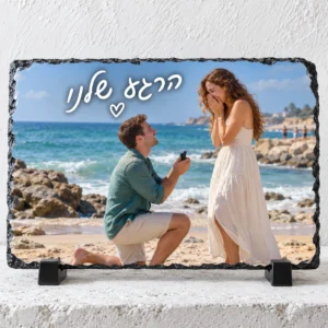 אבן בזלת מלבנית לרוחב עם הצעת נישואין בחוף וכיתוב לבן בכתב יד הרגע שלנו