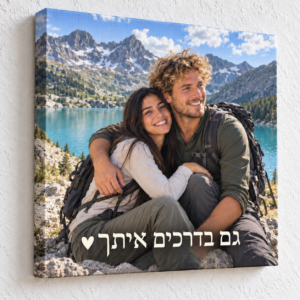 קנבס ריבועי עם זוג מטיילים והכיתוב גם בדרכים איתך ולב, על קיר בטון לבן מחוספס